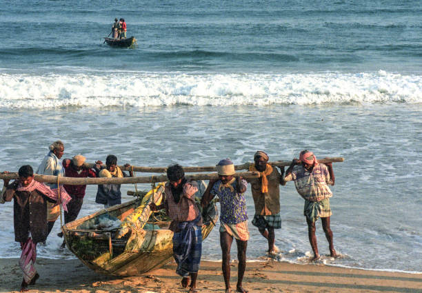 Gopalpur, Odisha, India. Fishermen carrying their boat towards the beach after fishing in afternoon.