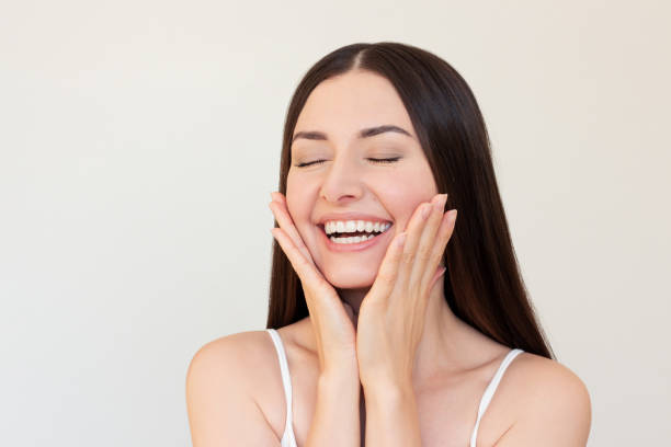 istock A young woman smiling, closing her eyes and touching her face with her hands. 2200614580