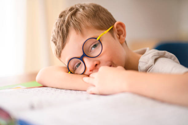 istock homework and school concept - tired student boy with book writing to notebook at home 2200614700