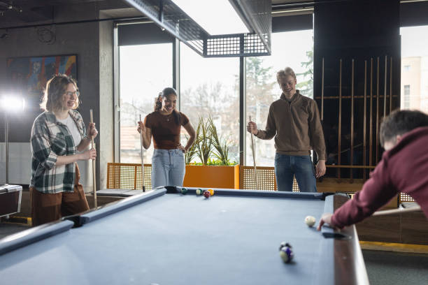 Group of cheerful young multiracial friends playing billiards in a local pool hall
