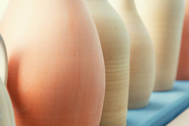 A close-up shot showcasing a row of terracotta pots, each with a unique shade and texture. The warm earth tones and subtle variations in color