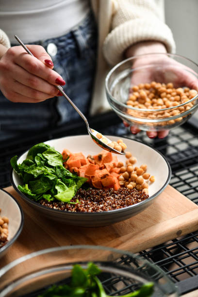 istock Female Adding Chickpeas to Delicious Nutritious Salad Bowl 2200619803