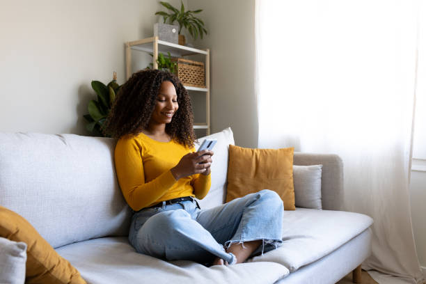 istock Young woman relaxing on sofa using smartphone at home 2200624100