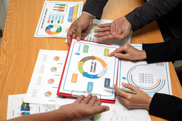 istock Business professionals discussing a startup strategy plan with charts and graphs on wooden table, analyzing company growth, investment opportunities, and financial planning 2200630869