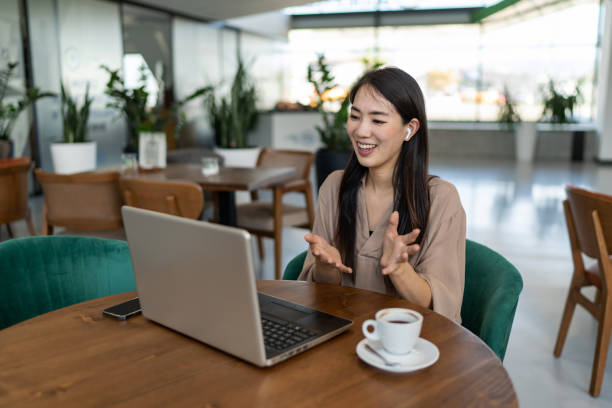 istock Smiling businesswoman talking with client via video call while sitting in cafe 2200631268