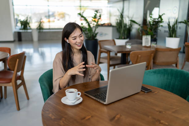 istock Smiling businesswoman talking with client via video call while sitting in cafe 2200631500