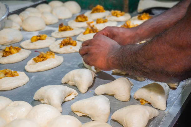 istock Image of baker's hand placing savory paste on dough / flour, potato, onion, vegetable bun ready to bake 2200633990