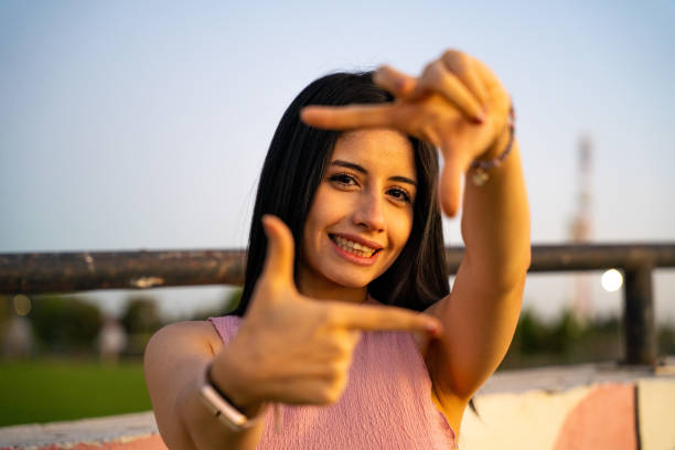 istock A woman dressed in a lovely pink dress is creating a frame shape using her hands 2200634212