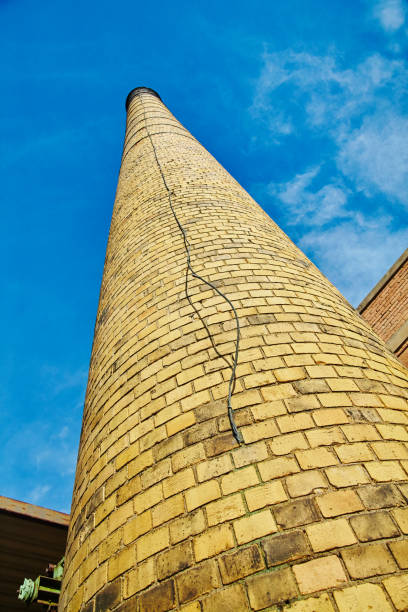 istock Industrial Brick Chimney with Weathered Texture Against Blue Sky, Low Angle View 2200634441