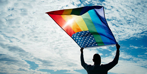 istock man waves a rainbow US flag on the sky 2200634594