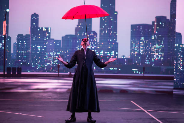 istock Mysterious Clown Performer with Red Umbrella in Urban Nightscape. 2200640446
