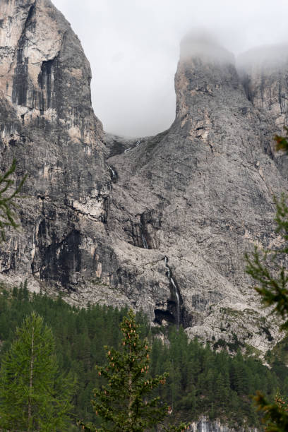 istock The source of the Pisciadu waterfall flows from mist covered Dolomite peaks down steep rocky cliffs framed by dense alpine trees in this vertical mountain scene 2200642614