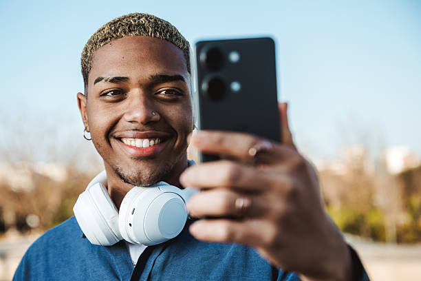 istock Young boy smiling looking at his mobile in a park 2200644739