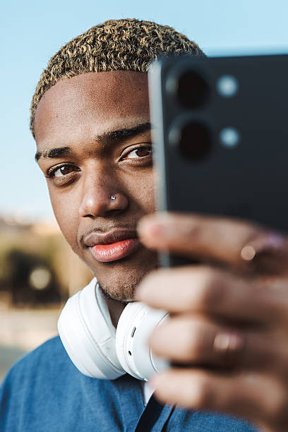 istock Portrait of a young afro guy looking at the camera with confident expression with his mobile in his hand 2200644789