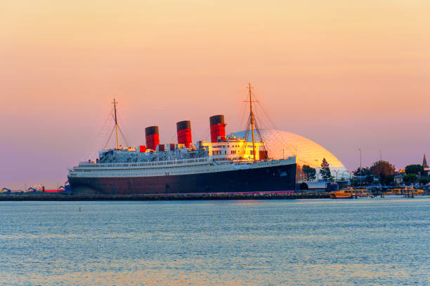 Long Beach, California - January 11, 2025: Iconic RMS Queen Mary illuminated by sunset, anchored in Long Beach with a colorful sky backdrop.