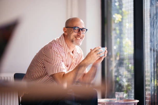 istock Smiling Man Enjoying Coffee Indoors By a Sunlit Modern Window 2200646624