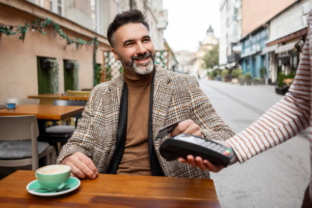Mid Adult Man Using A Credit Card In A Cafe