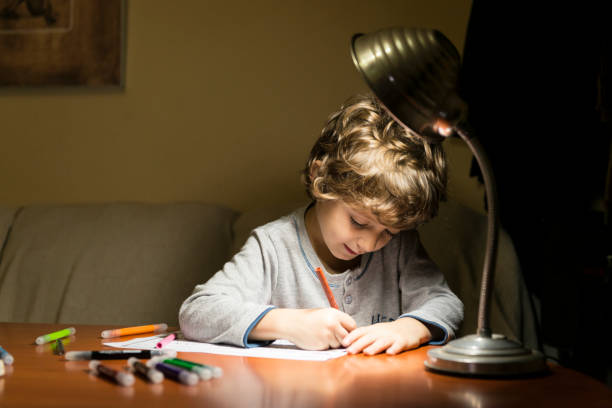 istock Child drawing illuminated by the light of a lamp. 2200648834