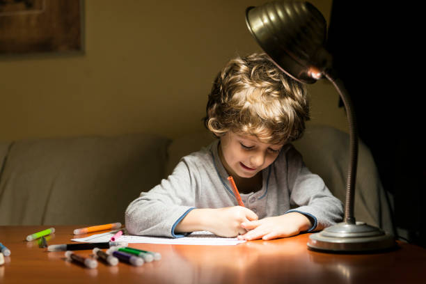 istock Child drawing illuminated by the light of a lamp. 2200648842