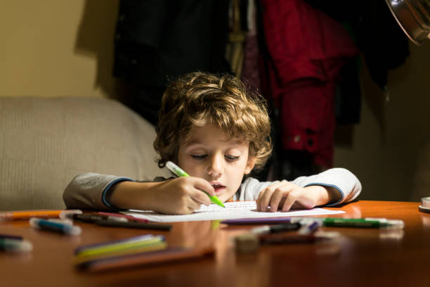 Child drawing with markers, illuminated by the light of a lamp.