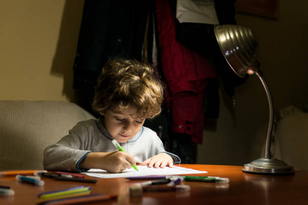 istock Child drawing illuminated by the light of a lamp. 2200648855