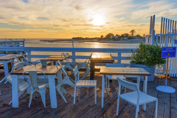 Malibu, California - November 29, 2024: Inviting setting with tables and chairs overlooking the sunset at Malibu Farm Restaurant, capturing the serene beachfront ambiance.