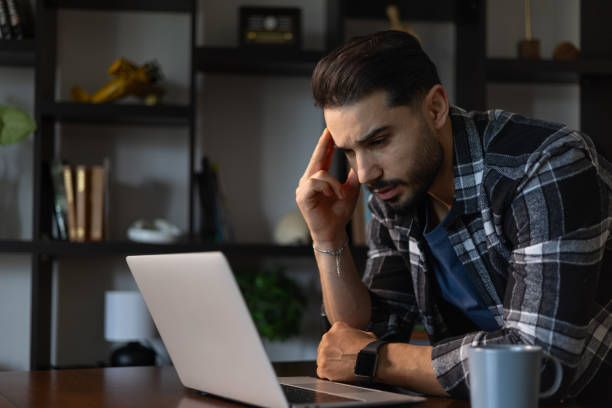 istock Young man working from home office using laptop and having a headache 2200656443