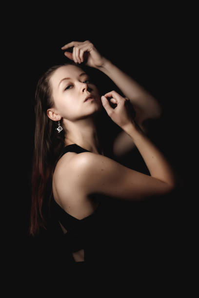 istock Woman gracefully posing against a dark backdrop, showcasing elegance and emotion in a dramatic, artistic style. Perfect for creative projects book cover copy space 2200656835