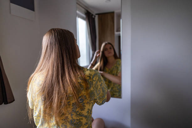 istock Woman Using a Flat Iron to Achieve a Sleek Look 2200657152
