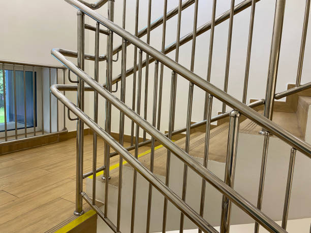 istock Flight of stairs. Modern chrome handrails with comfortable handrails at different heights for adults and children. First and last steps of stairs marked with yellow warning strip. Safety signs 2200657983