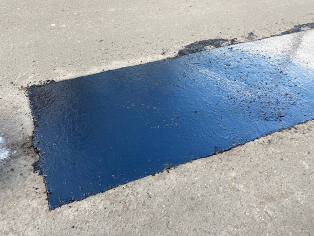 istock Large rectangular pit on the road filled with molten asphalt and bitumen. Poor, substandard repair of road surface. Partial restoration of surface 2200658221