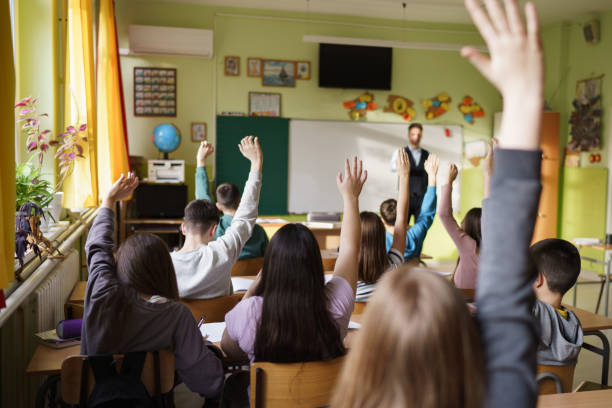 istock Children whit raised hands in the classroom 2200661700