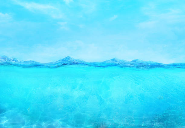 istock Underwater calm ocean wave surface and blue sky splitted by waterline. 2200663668