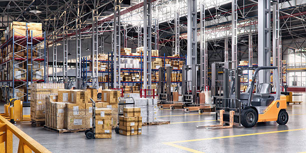 istock Modern warehouse interior with forklifts and stacked cardboard boxes on pallets 2200664160