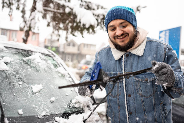 istock Man Cleaning Snow From Car Windshield in Winter Weather 2200667534
