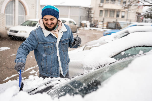istock Man Cleaning Snow Off Car in Winter Urban Environment 2200667544