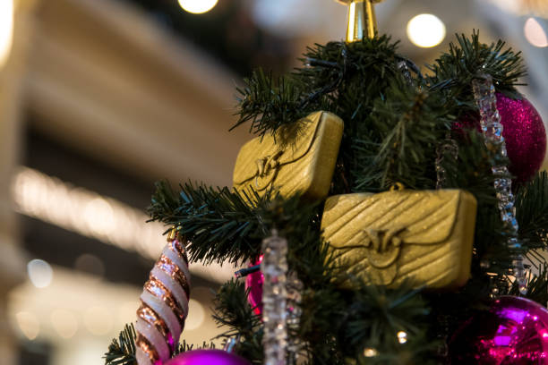 Bright gold decorations hang from a lush Christmas tree, accompanied by colorful ornaments and shimmering accents. This festive display captures the holiday spirit in a joyful setting.