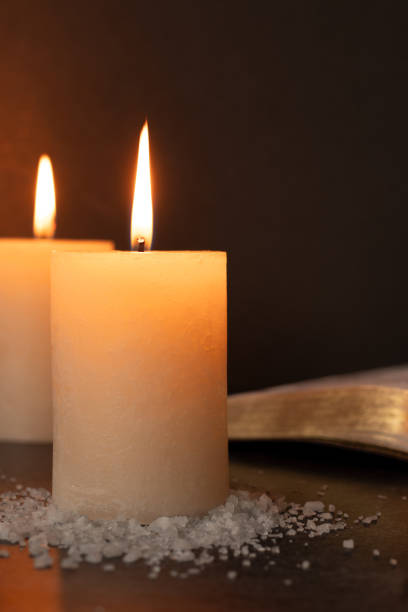 istock Candle and salt with open holy bible book 2200674509