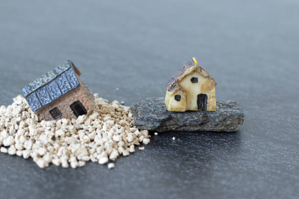 istock Two miniature houses in sand and rock 2200674725