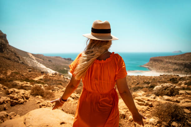 istock Woman relaxing on rocky cliff overlooking scenic coastal view 2200681884
