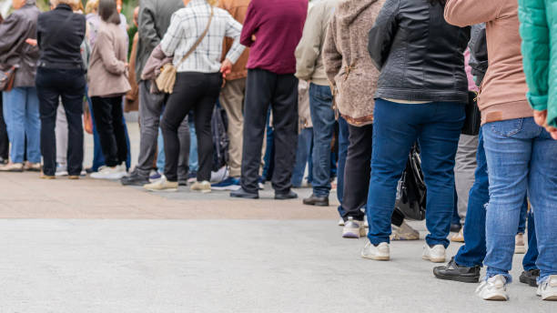 grupo de personas diversas anónimas que hacen cola al aire libre, larga fila de hombres y mujeres, vista trasera. concepto de espera, paciencia, vida urbana - desempleados fotografías e imágenes de stock