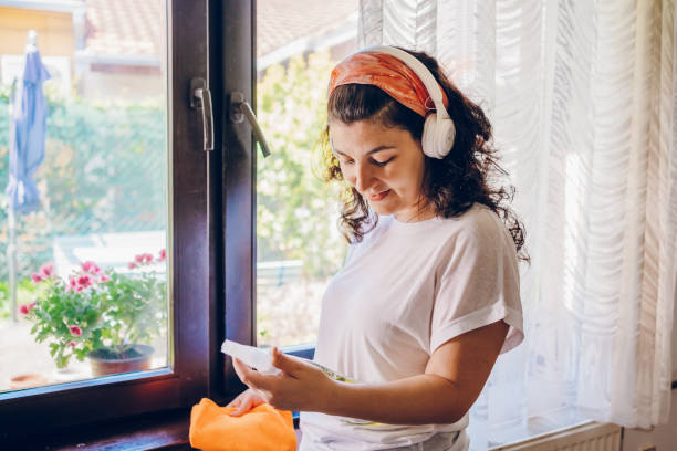 a woman cleans her home while listening to music - リスニング 家事 ストックフォトと画像