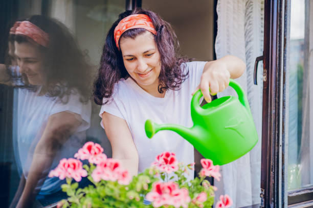 istock Beautiful woman is watering the flowers 2200688012