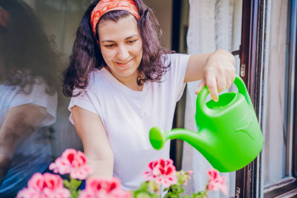 istock Beautiful woman is watering the flowers 2200688024