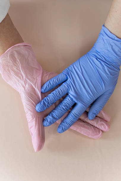 istock Hands with pink and blue gloves touching each other on a neutral background 2200696284