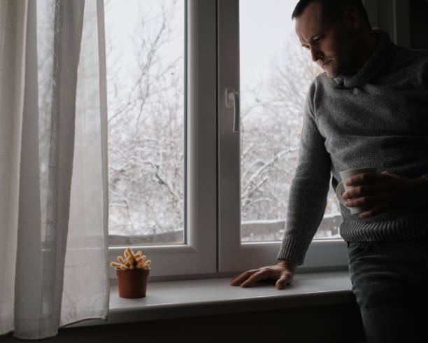 istock A young handsome man sits by the window and drinks his morning coffee. It's a winter idyll outside. 2200700180