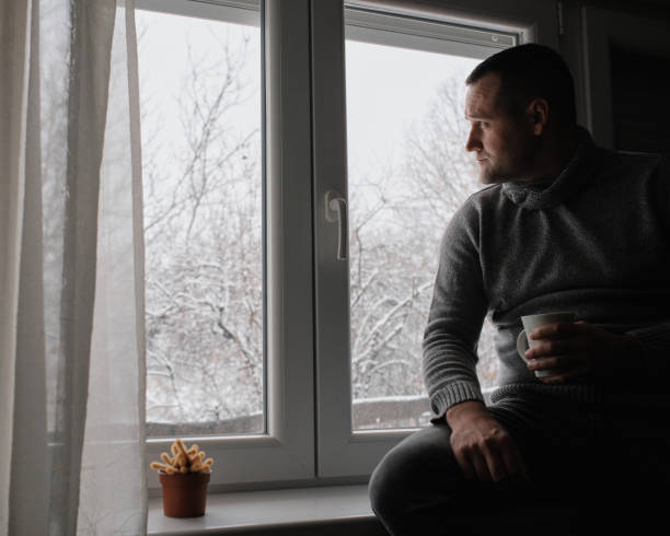 istock A young handsome man sits by the window and drinks his morning coffee. It's a winter idyll outside. 2200700342