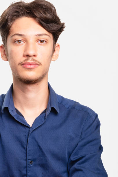 istock Young handsome student in blue shirt looking seriously at camera. Isolated on white background. Confident person. 2200702754
