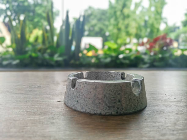 istock Ceramic ashtray containing cigarette ash or cigarette butt holder placed on a wooden table 2200702856