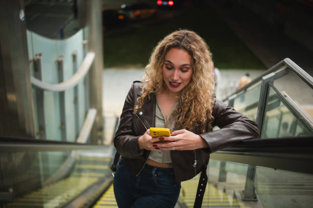 istock Young woman engaging with smartphone on escalator 2200705570